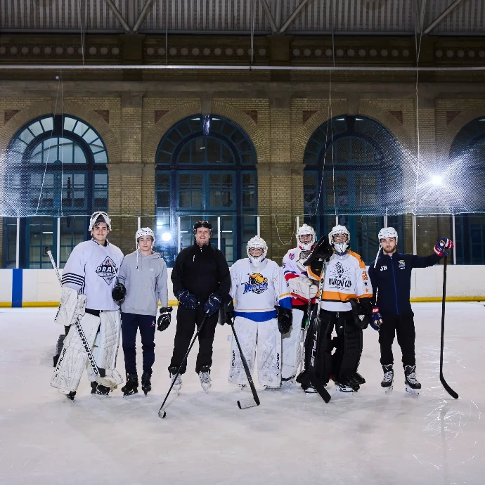 Coach Matt Darlow standing on ice with goaltenders and coaching staff.